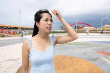 Yorgun bir kadın yaz caddesinde kendini ateşli hissediyor.