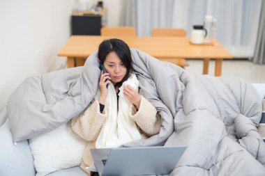 Evde telefonla konuşan hasta bir kadın var.