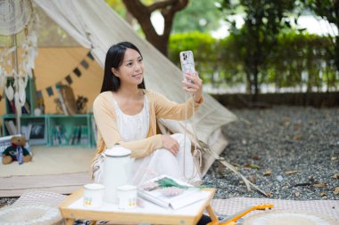 Dışarıda selfie çekmek için cep telefonu kullanan genç bir kadın.