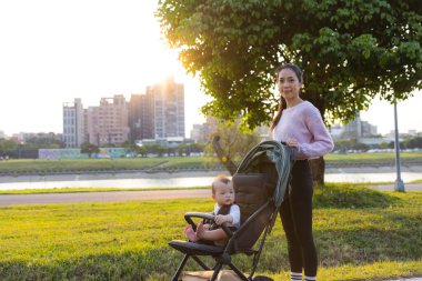 Bebek arabasındaki bebek annesiyle parka gidiyor.