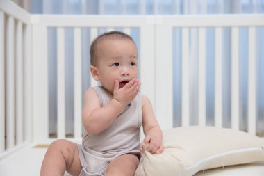 Bebek çocuk evde küçük elleriyle ağzını kapatıyor.