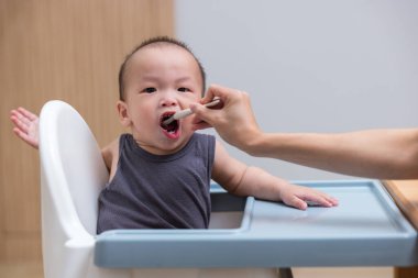 Mutlu çocuk kaşıkla ezilmiş yemek yiyor.