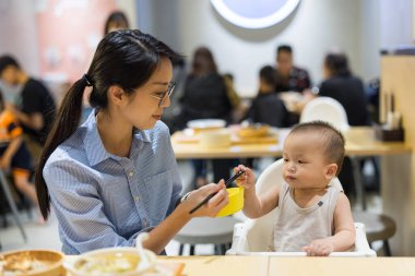 Annesi lokanta masasında bebeğini besliyor.