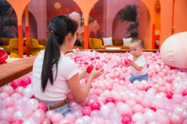 Anne top havuzunda bebekle neşeyle oynuyor.