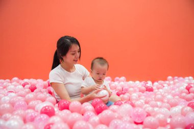 Anne oğluyla top havuzunda pembe renkte oynuyor.