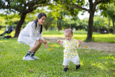 Küçük oğlum, annesi arkasındayken çimenlerde yürümeye çalış.