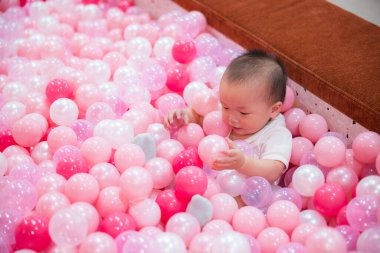 Mutlu bebek pembe top havuzunda oynuyor