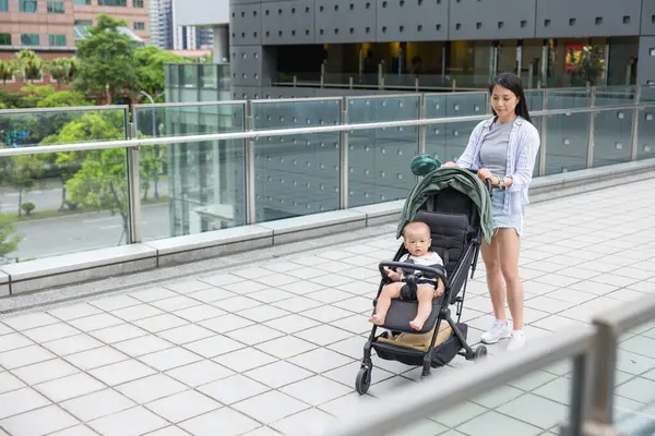 Anne kucağında bebekle şehir merkezinde yürüyor.