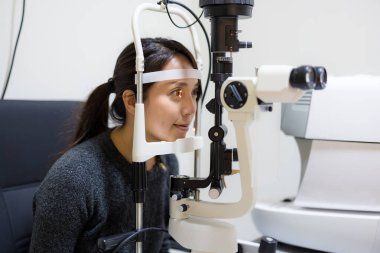 Woman checking eyesight at eye clinic medical examination