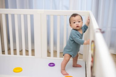 Toddler having fun in playpen at home