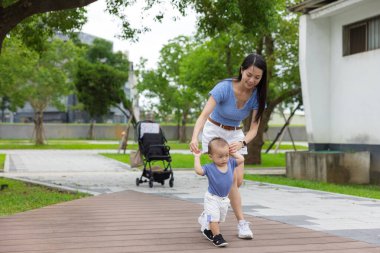 Mother walking with baby in green park