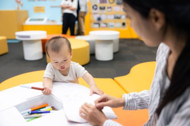 Mother with her son draw on the paper together at playhouse