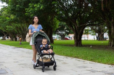 Mother walking with baby in stroller at park
