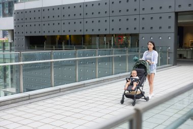 Anne, bebek arabasını it. Sokakta yürüyor.