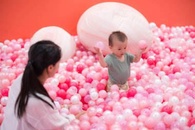 Anne top havuzunda bebekle oynuyor.