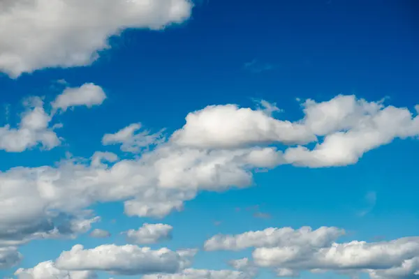 鮮やかな青い背景に漂う散らばったふわふわの白い雲を特徴とするダイナミックなスカイシーンは 深さと動きに満ちた美しい景色を提供します — ストック写真