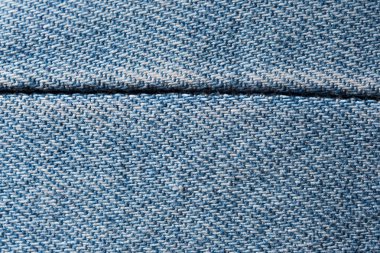 Close-up view of light blue denim showing textured weave and a detailed horizontal seam.