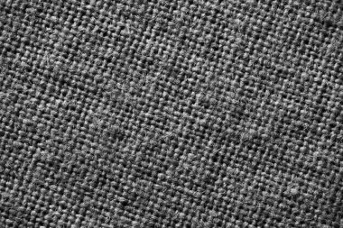 Close-up black and white image of coarse burlap fabric showing thick threads and loose weave.