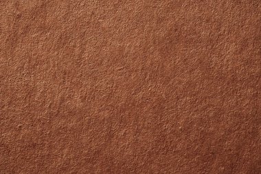 Macro photo of reddish-brown recycled paper with fibrous surface and natural, rough texture.