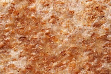 Macro view of a golden, flaky flatbread with crispy layers and toasted grains.