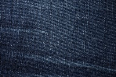 Detailed macro shot of dark blue denim fabric with visible diagonal weave pattern and subtle fading.