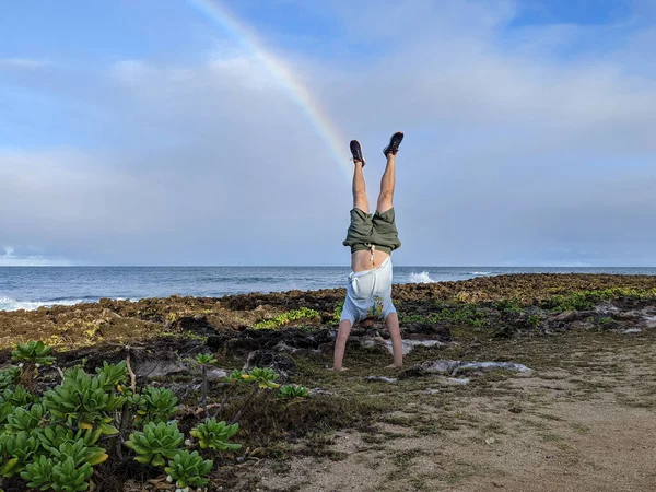 Człowiek Stoi Koralowych Skałach Plaży Tęczą Niebie Gdy Fala Rozbija — Zdjęcie stockowe