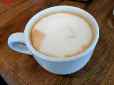 Beyaz fincan Cappuccino büyük beyaz nokta ahşap masa üzerinde köpük ile.