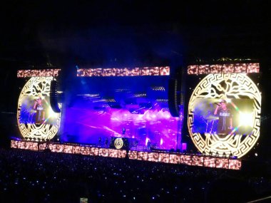 Honolulu - 8 Kasım 2018: Bruno Mars, Hawaii 'deki Aloha Stadyumu' ndaki konser sırasında gösterilen LED ekranlarda bando çalarken mikrofona şarkı söyledi..