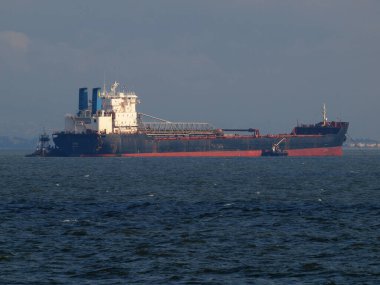 San Francisco - January 30, 2011:  large cargo boat being propelled through the misty waters of the San Francisco Bay. The powerful tug boats guide the ship through the fog, showcasing the might of modern shipping. 