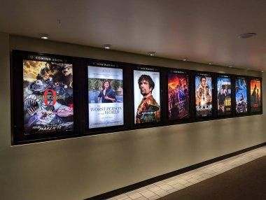 Honolulu - March 11, 2022:  Row of movie posters including Jujusu Kaisen, The worst person in the world, Cyrano, Death on the Nile, Uncharted, Dog, Spider-Man, and Batman on wall located outside the movie theater at the Kahala Mall. clipart