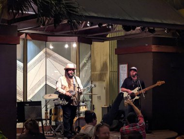 Waikiki - 24 Mart 2022: The Guidance Band Waikiki, Hawaii 'deki Hilton Hawai Village Tapa' s Bar 'da canlı olarak çalıyor. Grup dört üyeden oluşuyor ve çeşitli popüler şarkılar çalıyorlar. Grup sahnelenen sahnede çalıyor.