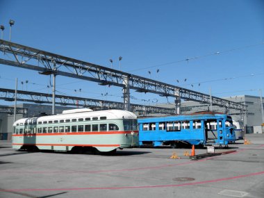 San Francisco - 18 Haziran 2010: Muni tren istasyonunda yeniden boyanmış ve paslı bir Muni treni. Yeniden boyanmış tren kırmızı ve beyaz renk düzeniyle parlak ve parlaktır. Paslı tren soyulmuş boyayla donuk ve kirli..