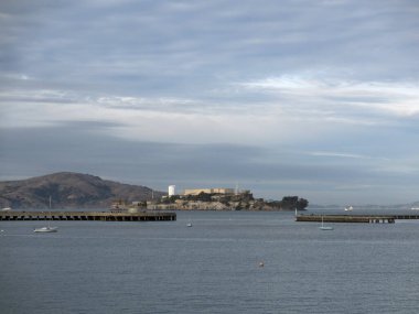 San Francisco - 28 Aralık 2011 körfeze doğru uzanan uzun iskele bulutlu bir gökyüzünün altındaki Alcatraz Adası 'na doğru ilerliyor. Fotoğrafta sakin sulara dağılmış birkaç küçük tekne görülüyor, bu da sakin atmosfere katkı sağlıyor. Bu fotoğraf bir...