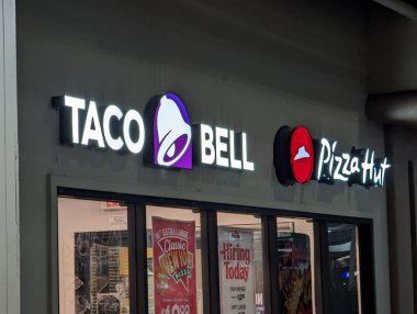 Honolulu - 6 Aralık 2022: Taco Bell ve Pizza Hut mağazaları geceleri bir alışveriş merkezinde. Mağaza vitrininde beyaz harfli ve logolu siyah bir tente var. Pencerelerde reklamlar ve işe alım işareti var. Otopark ve diğer dükkanlar manzaralı.