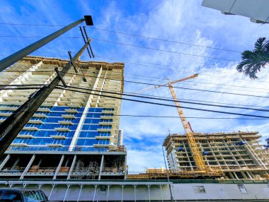 Honolulu - 19 Kasım 2023: Bu dinamik görüntü Honolulu 'daki kentsel gelişimin karmaşık sürecini yakalar. Parçalı bulutlu bir gökyüzünün arkaplanına karşı inşaat işçileri özenle bina iskeleti ve hareketleri üzerinde çalışıyorlar. 