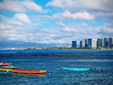 Geyik Locası 'nın tepesine tünemiş Waikiki' nin panoramik manzarası canlı bir duvar halısı gibi açılır. Pasifik 'in masmavi suları ufka doğru uzanıyor. Yumuşak dalgaları kumlu kıyıları kucaklıyor. Yüksek binalar, balkonlarla süslenmiş ve kazanılıyor.