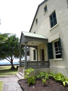 Tropikal bitkiler ve deniz manzaralı yeşil panjurlu tarihi bir bina girişi. Hawaii, Kailua-Kona 'daki Hulihee Sarayı Kailua' daki Ali 'i Yolu üzerinde yer almaktadır - Kona, Hulihe' e Sarayı Hawaii kraliyet ailesinin tatil yeriydi.. 