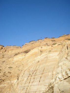 Kaliforniya 'da engin bir mavi gökyüzüne karşı engebeli bir sahil uçurumunun zirvesinde tek başına uçan bir kuş görülebilir..