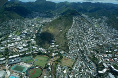 Honolulu - April 20, 2016: Honolulu city intertwines with nature, showcasing buildings of UH College nestled against lush mountains, Manoa Valley and St. Louis Heights. clipart