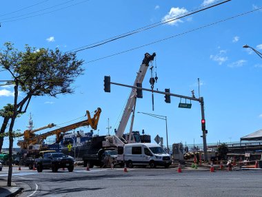 Honolulu - 4 Kasım 2023: Aydınlık, güneşli bir günde işçiler aşağıda dururken bir vinç trafik ışığını kaldırır.