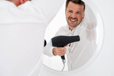 Hiperhidrozlu bir adam koltuk altında çok kötü terliyor ve vantilatörle kurutmaya çalışıyor. Randevudan ya da yemekten önce sinirlen.