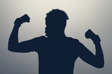 Bilinmeyen erkek silueti stüdyodaki kaslarıyla gurur duyuyor. Sağlıklı yaşam tarzı kavramı