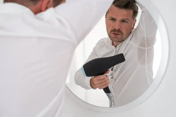 stock image Man with hyperhidrosis sweating very badly under armpit trying to dry it with fan. Get nervous before date or meating