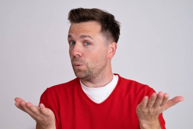 Kafkasyalı bir adamın elleri ve kolları havada, kafası karışık bir ifadesi var.. 