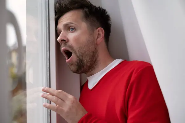 stock image Caucasian man peeking through window being shocked with accident on street. Phobia to leave home