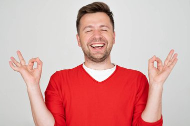Olgun bir adam rahatlıyor ve gözleri kapalı gülümsüyor parmaklarıyla meditasyon hareketi yapıyor. yoga konsepti. 
