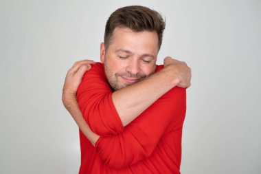 Confident smiling man holding hugging himself. Positive human emotion, facial expression. Love yourself concept clipart