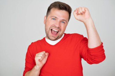 Heyecanlı beyaz adam başarıyla yumruklarını kaldırıyor. Olumlu yüz insani duygu