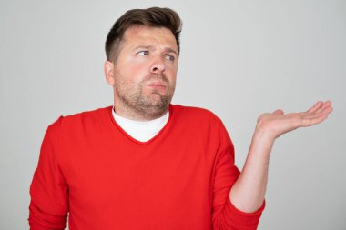 Kafkasyalı bir adamın elleri ve kolları havada, kafası karışık bir ifadesi var.. 