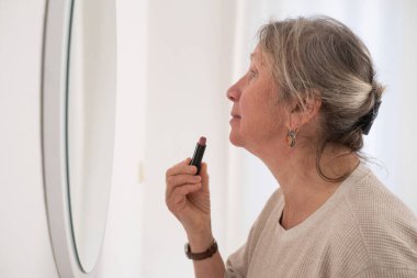 Dudaklarına ruj süren son sınıf öğrencisi çekici bir kadın. Güzel, olgun bir bayan güzellik ve yüz bakımının tadını çıkarıyor. Dekoratif kozmetik ürünler kullanıyor.. 